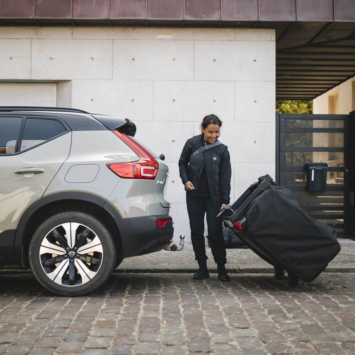 Person setting up Thule Thule Outset 3-person towbar-mounted car tent beside a car.
