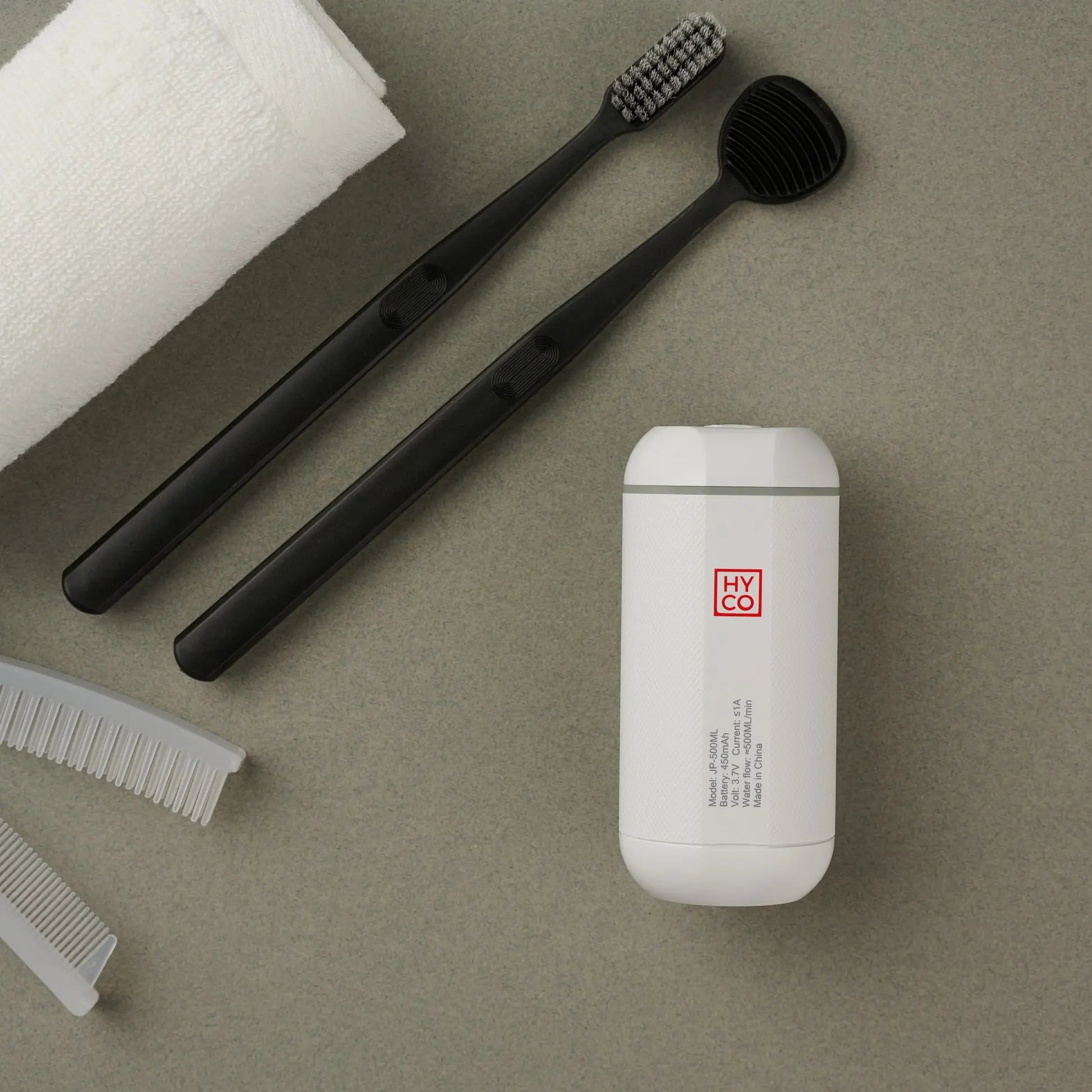 Hygiene Collective Mist - Portable Bidet next to toothbrushes, comb, and towel for personal cleanliness on the go.