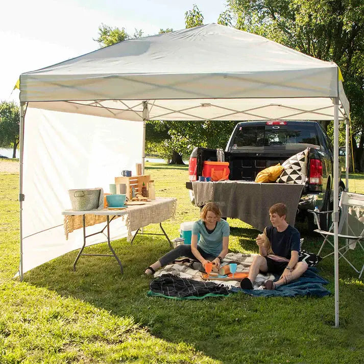 Family enjoying outdoor picnic under a canopy with Core Equipment Sun Wall Accessory providing shade and privacy.