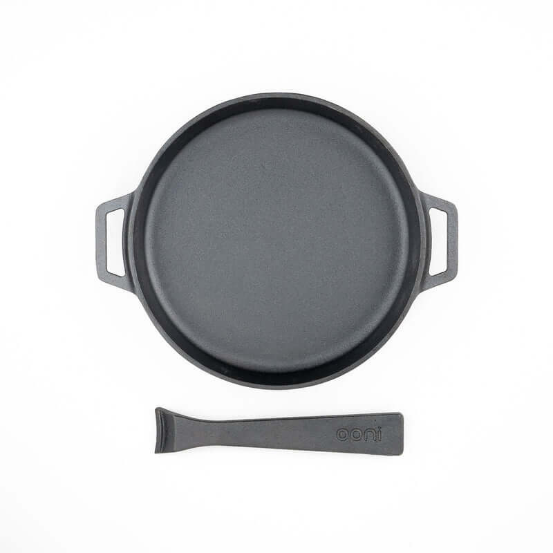 Top-down view of the Ooni Cast Iron Skillet Pan resting on its wooden serving board