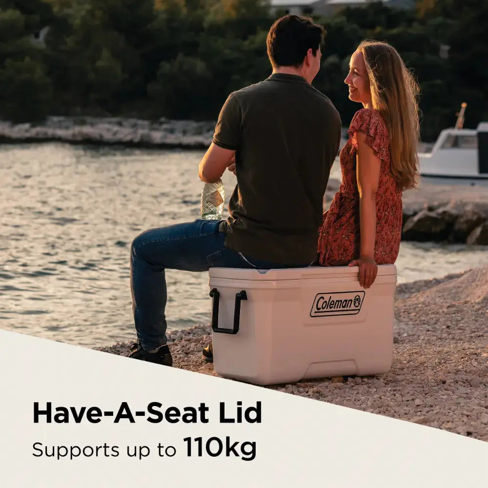Couple sitting on Coleman Xtreme Marine 70Qt cooler with Have-A-Seat lid by the sea
