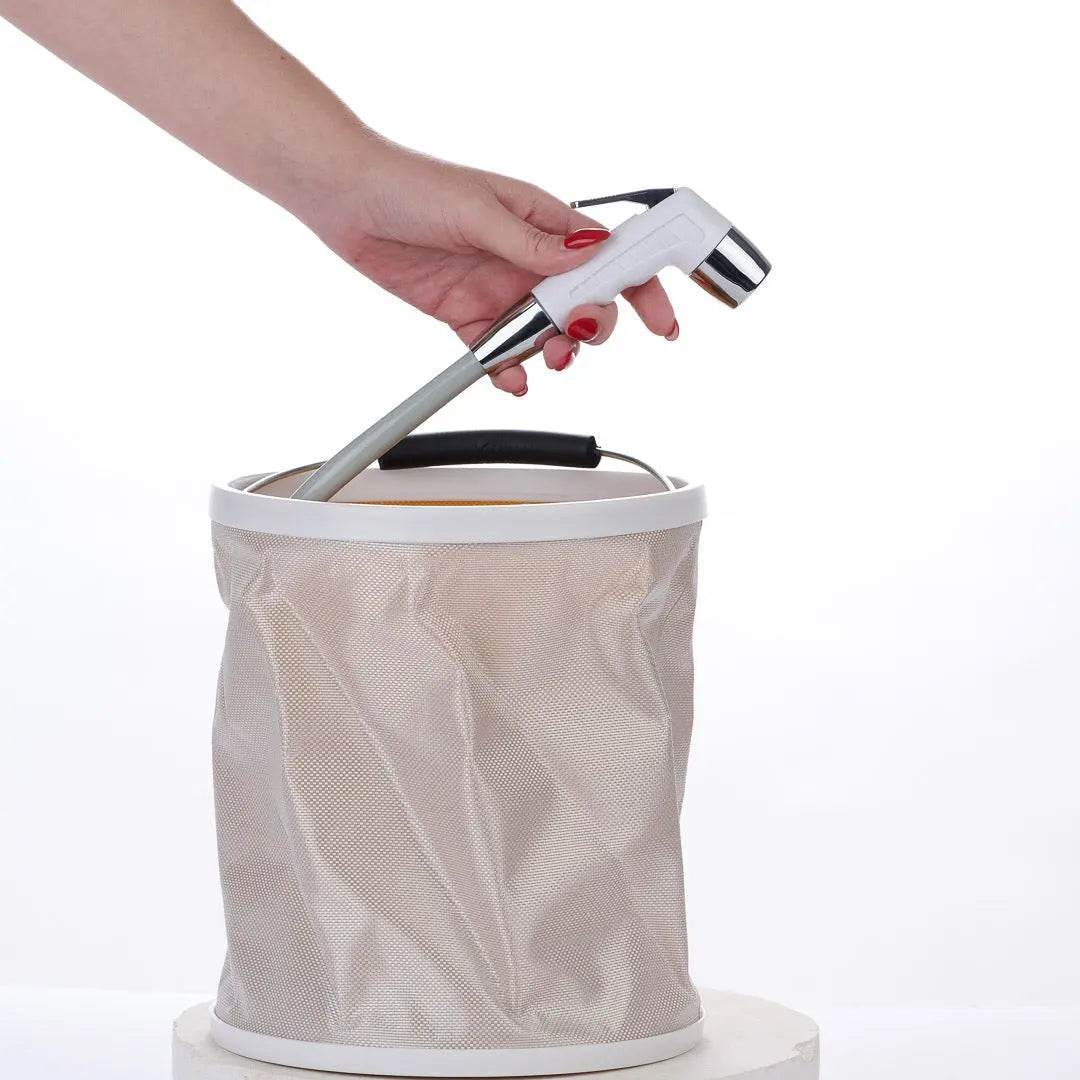 Person demonstrating the Hygiene Collective Folding Bucket - 8L Portable with a water spout handle.