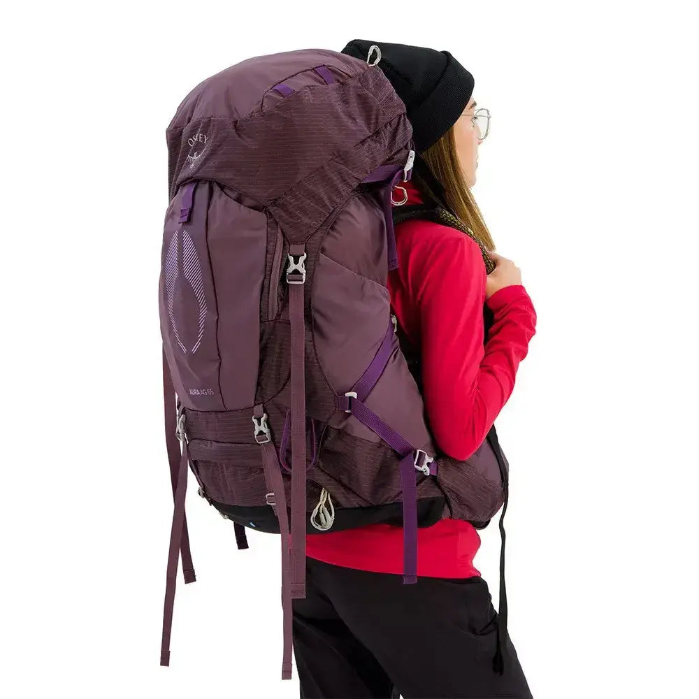 Osprey Aura AG 65 - Women backpack offering comfort and ventilation, shown on a model wearing a red jacket.