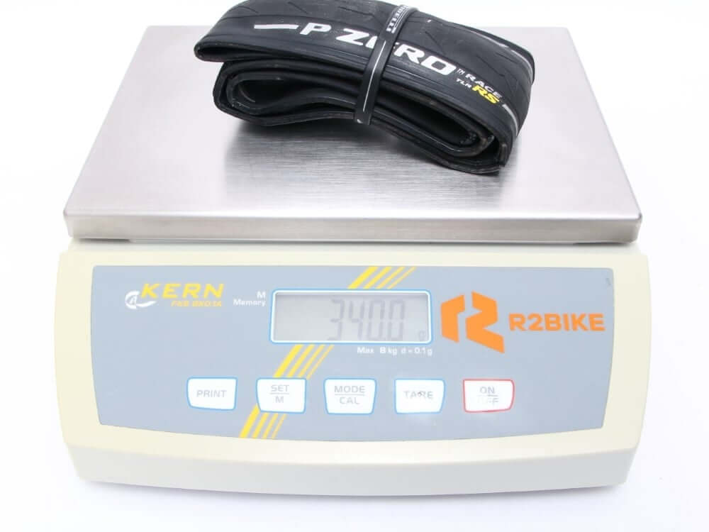 Pirelli P Zero Race RS Tubeless Ready Tire on digital scale demonstrating lightweight for high-performance cycling.