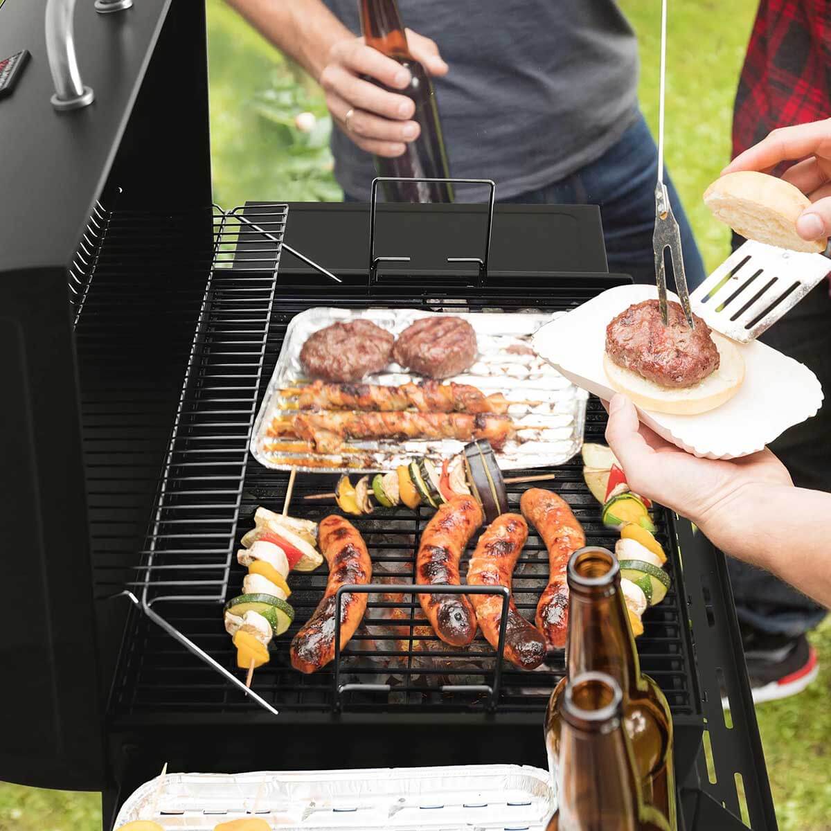Royal Gourmet 28-Inch Barrel Charcoal Grill with Front Basket being used by people