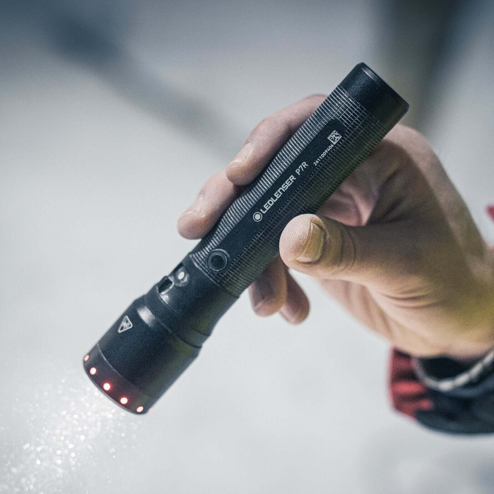 Hand holding the P7R flashlight showcasing its focus and light modes in action.