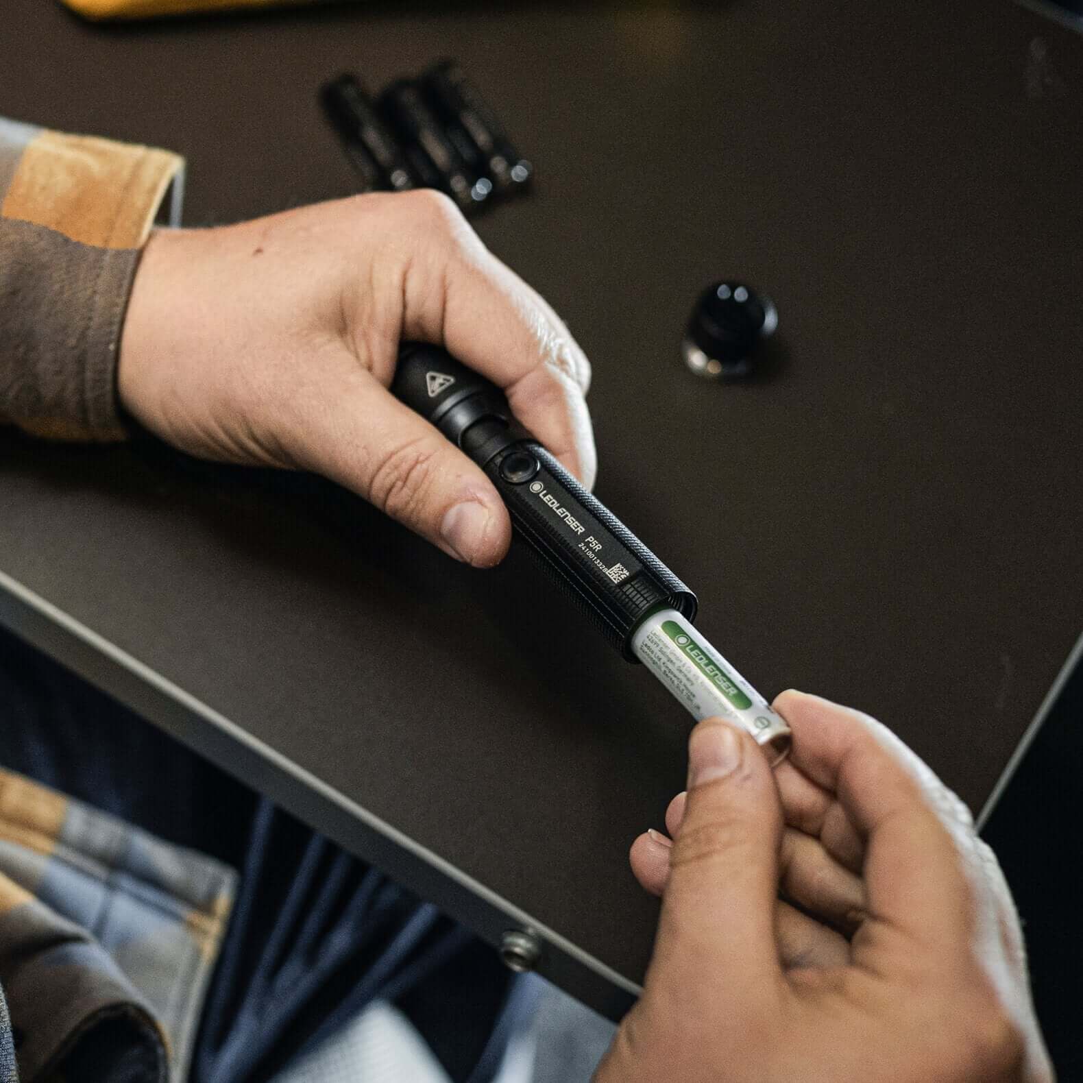 Person inserting a rechargeable battery into the P5R flashlight for optimal performance.