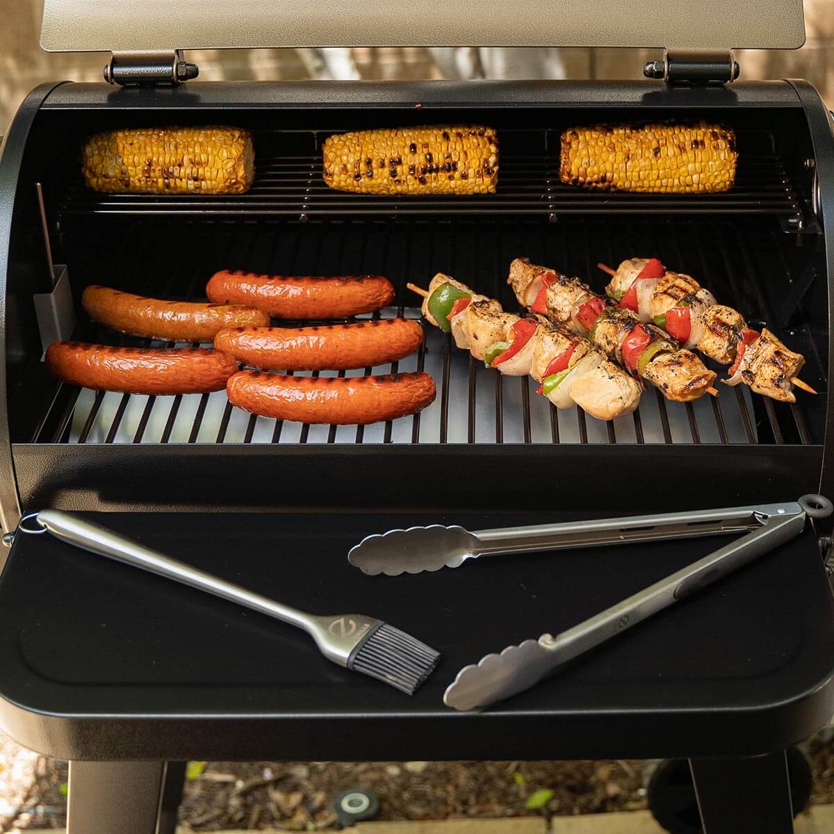 Z Grills Wood Pellet Grill and Smoker 450A cooking sausages, corn, and skewers outdoors