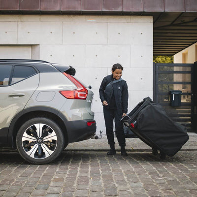 Person setting up Thule Thule Outset 3-person towbar-mounted car tent beside a car.