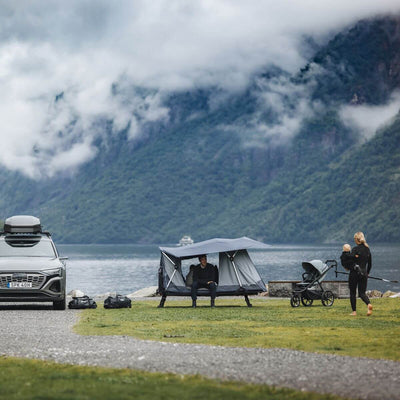 Family enjoying nature with Thule Thule Outset - 3-person towbar-mounted car tent by a lake.