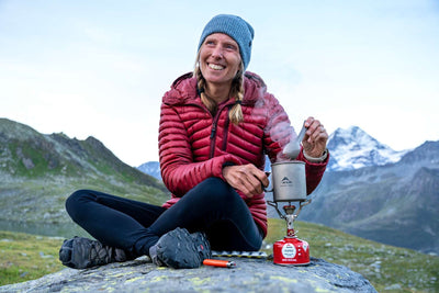 Camper using MSR PocketRocket 2 Stove in mountain setting, highlighting its lightweight and portable design for outdoor adventures.