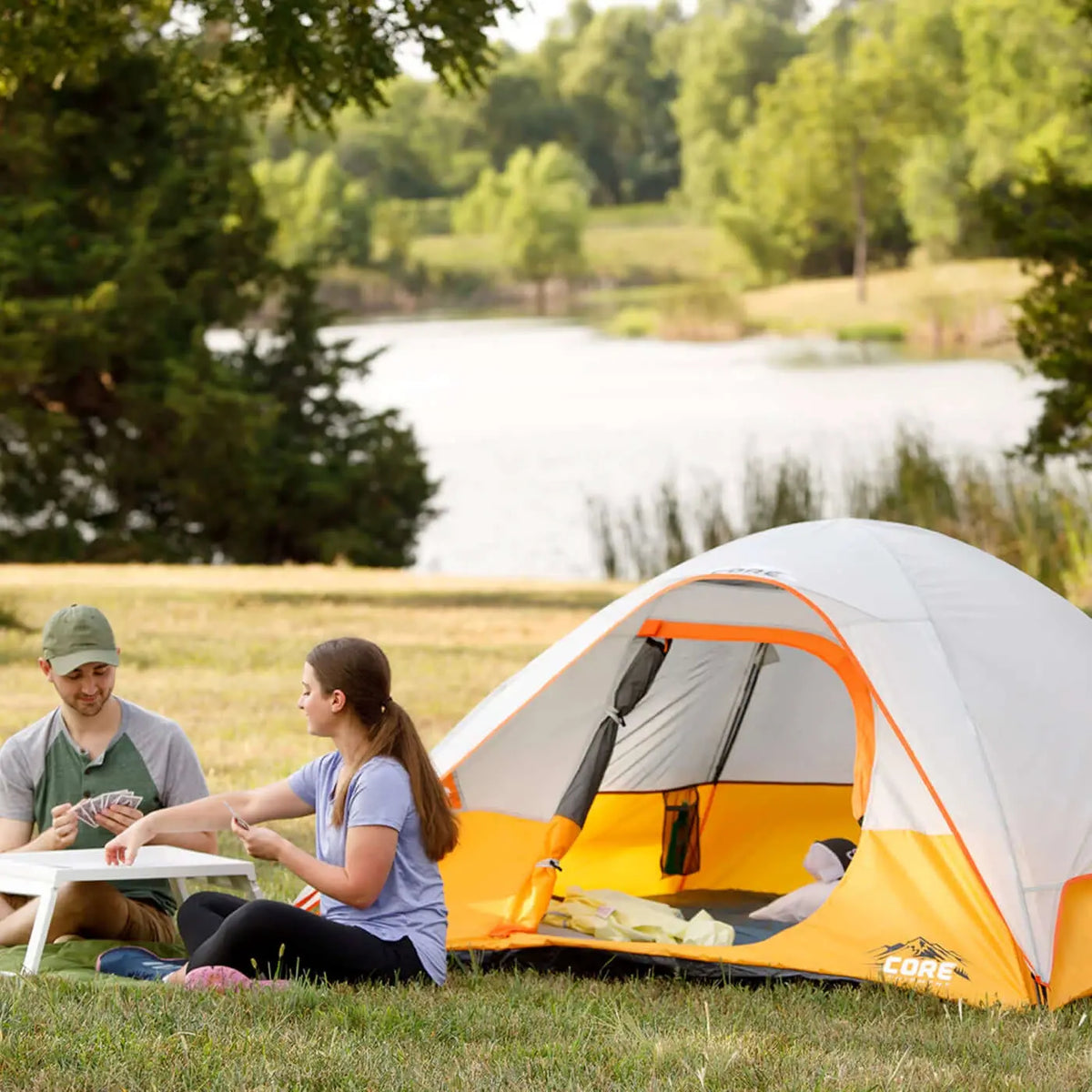 3 Person Dome Backpacking Tent - 7' x 7' set up by a lake with two people enjoying the outdoors.