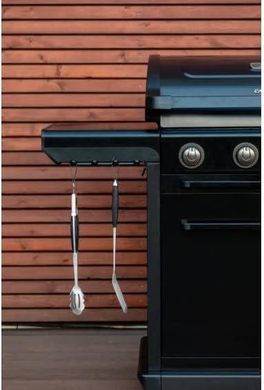 Side view of Campingaz 4 Series Onyx S Outdoor Gas BBQ Grill with cooking utensils hanging