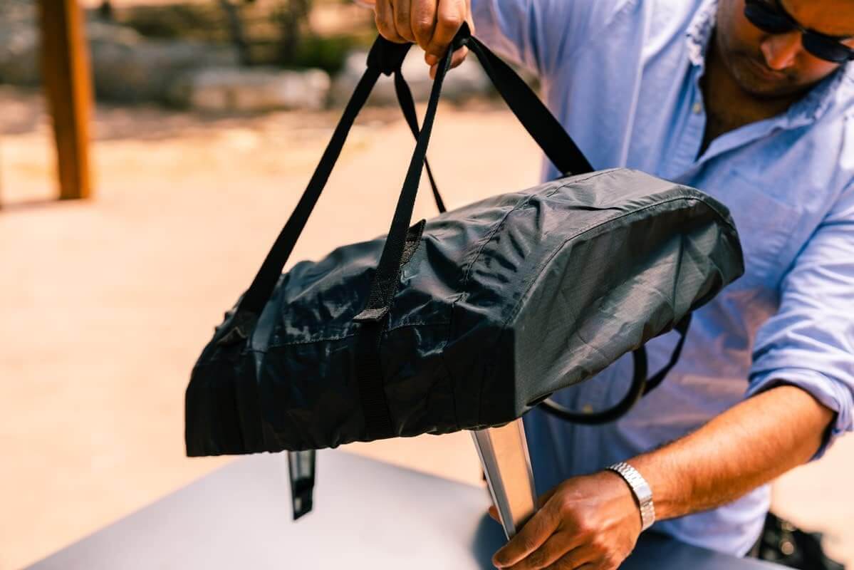 Person using Ooni Carry Cover for Ooni Koda 12 to protect and transport outdoor pizza oven.