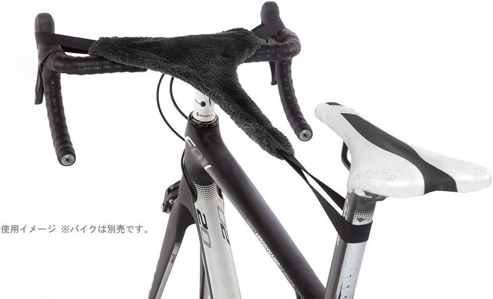 A black fuzzy handlebar tape cover draped over bicycle drop handlebars, shown on a white background with part of the bike frame and saddle visible.