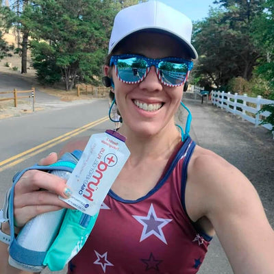 Smiling athlete holding Huma Chia Energy Gel Plus - Berries & Pomegranate during outdoor run