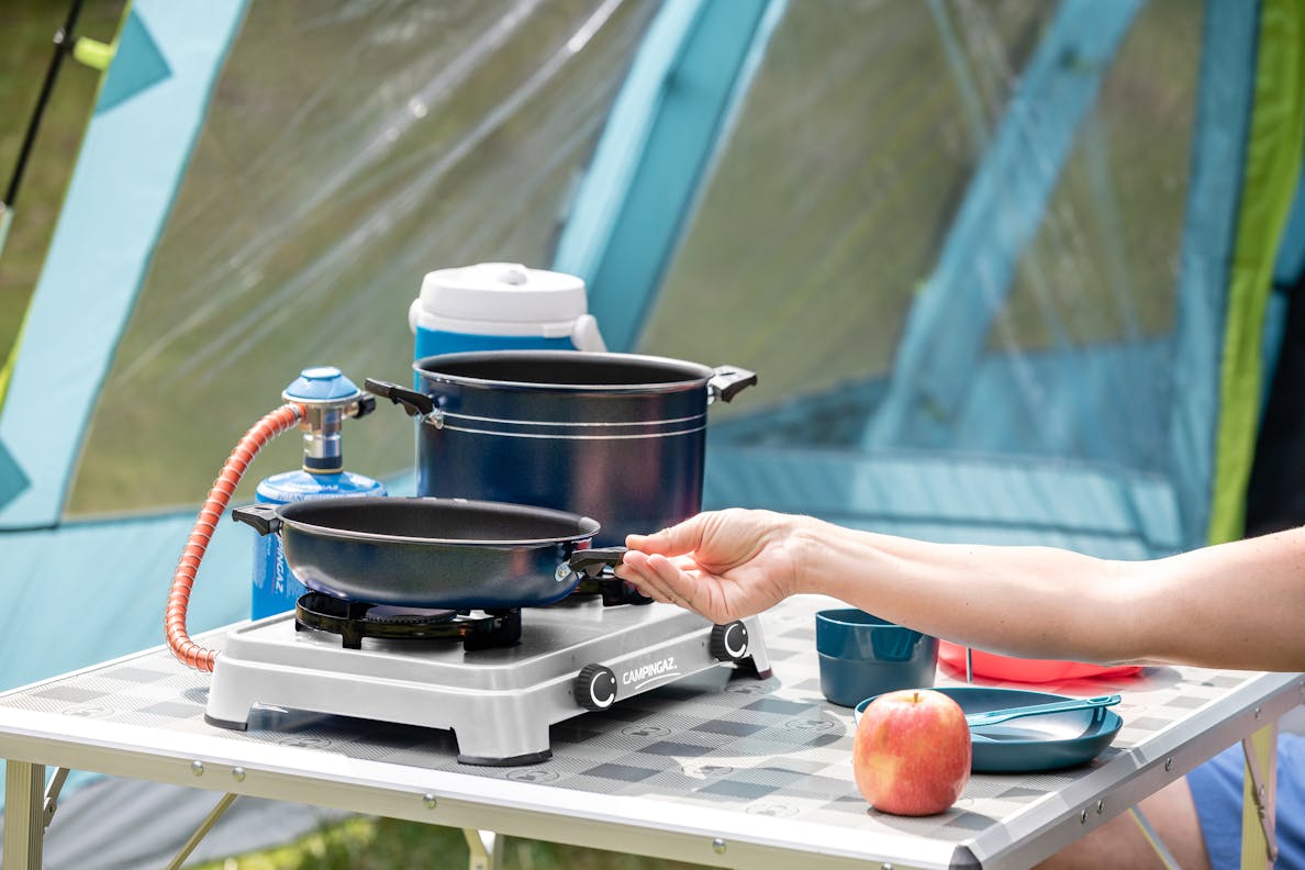 Campingaz Camping Cook CV portable stove set up in a camping scenario with cookware and an apple on a table