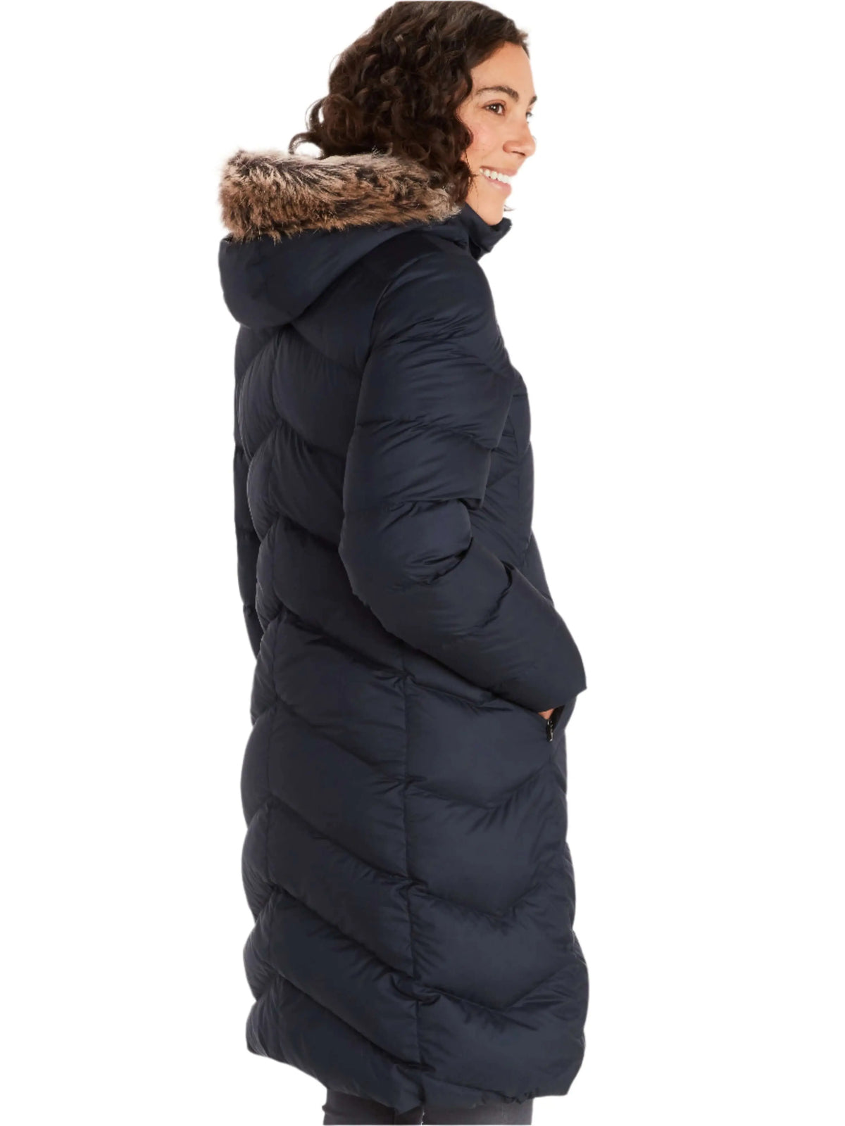Woman wearing Marmot Montreaux Coat, a women's winter down jacket, showing back view with fur-trimmed hood.