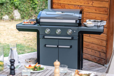 Campingaz 3 Series Premium S Gas Grill in backyard setup with side shelves, perfect for outdoor cooking and gatherings.