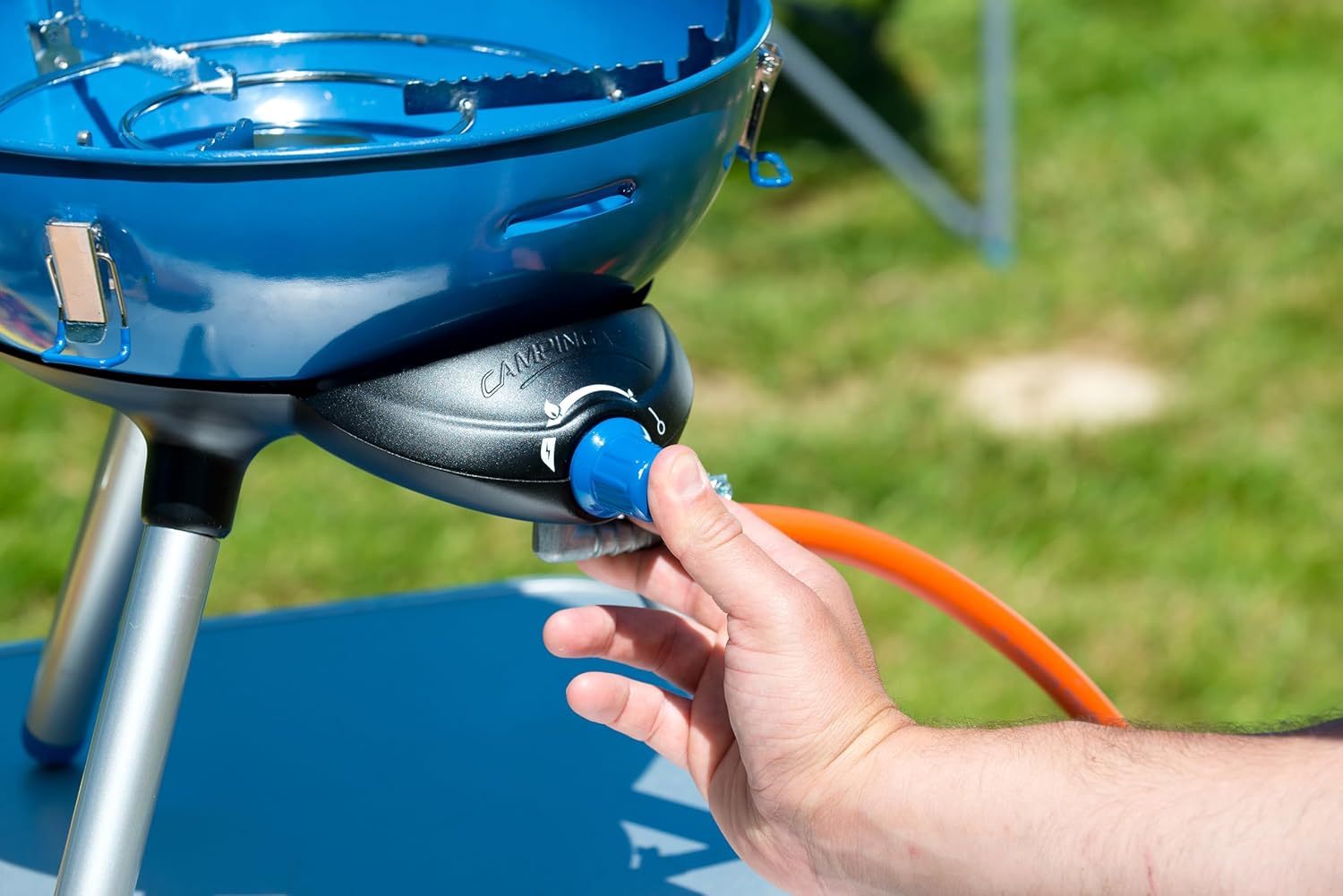 Hand connecting gas to Campingaz Party Grill 400 for outdoor cooking
