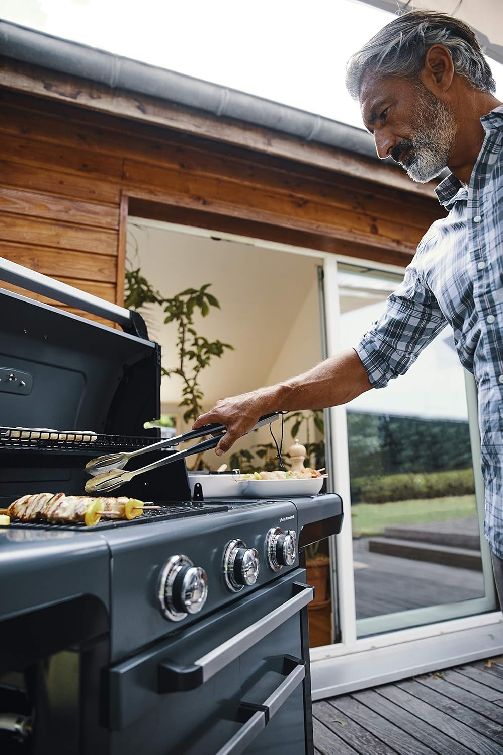 Man grilling food on Campingaz 3 Series Premium S Gas Grill on terrace