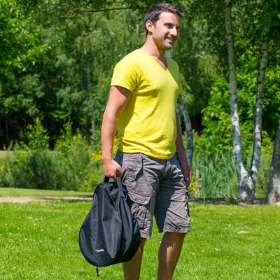 Man carrying Campingaz Party Grill 400 in a bag outdoors