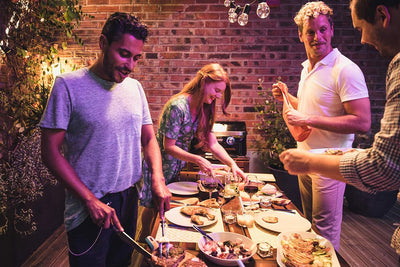 Friends using Campingaz Attitude 2100 LX Portable Gas Grill for an outdoor dinner party