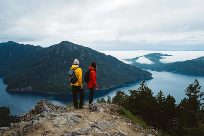 Hikers overlooking a mountain lake, wearing vibrant jackets for outdoor exploration, exemplifying the Marmot Gore-Tex Minimalist Pro Jacket.