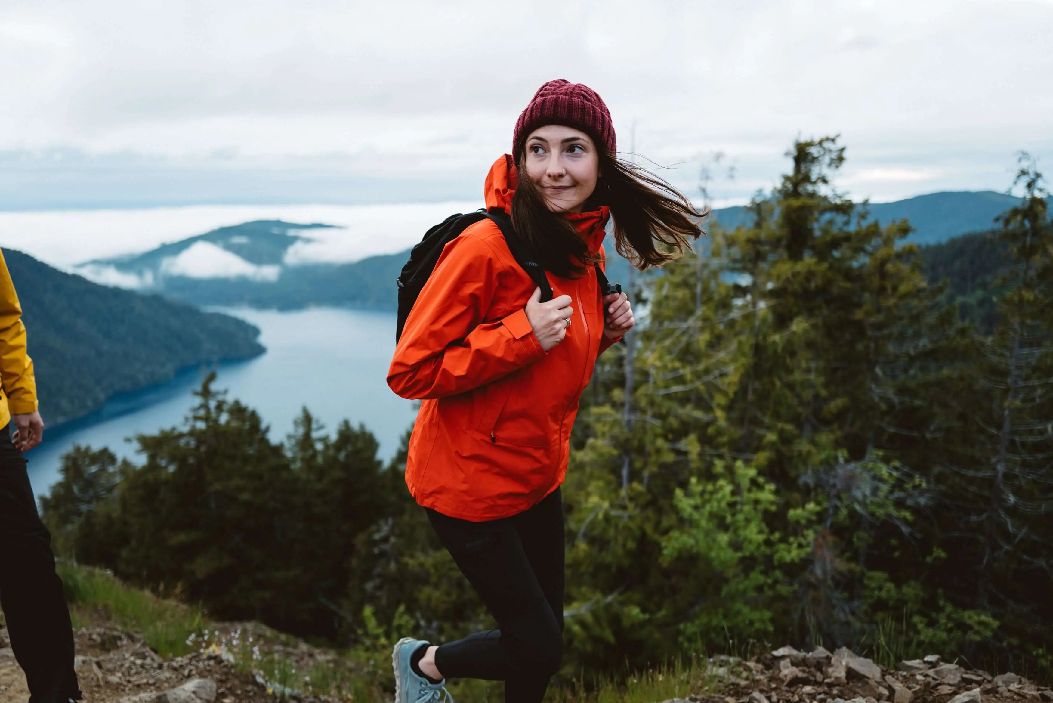 Woman hiking in orange Marmot Gore-Tex Minimalist Pro Jacket with scenic mountain view