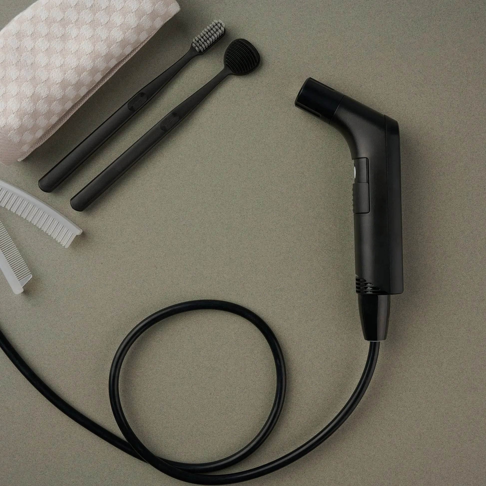 Hygiene Collective Bliss Rechargeable Travel Bidet with accessories including brushes and cloth on a beige surface.