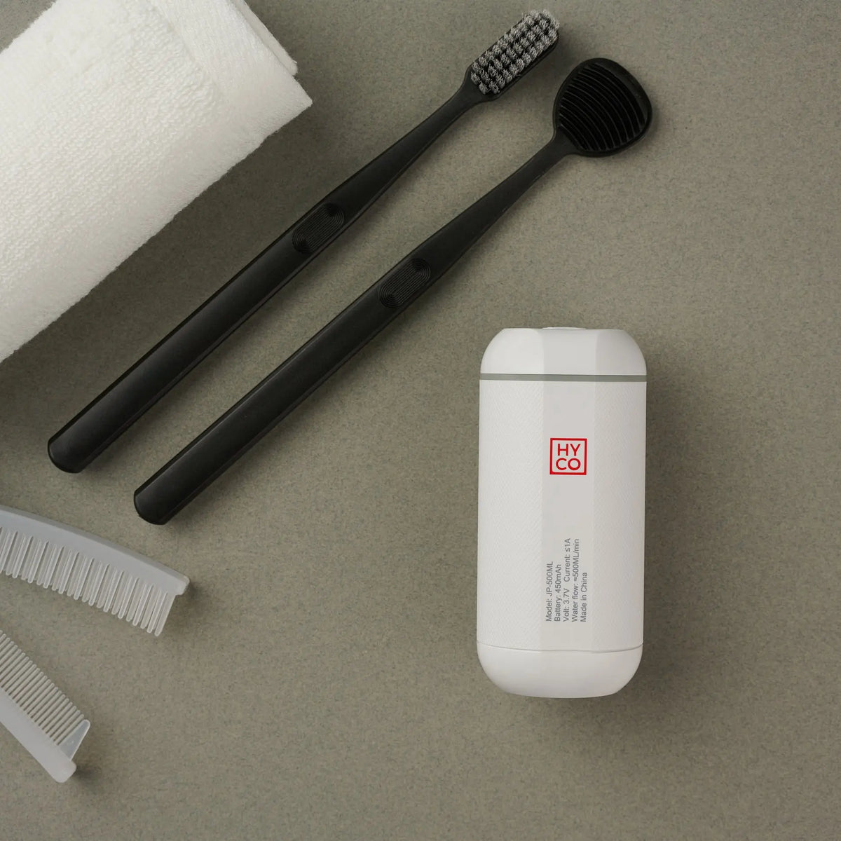 Hygiene Collective Mist - Portable Bidet next to toothbrushes, comb, and towel for personal cleanliness on the go.