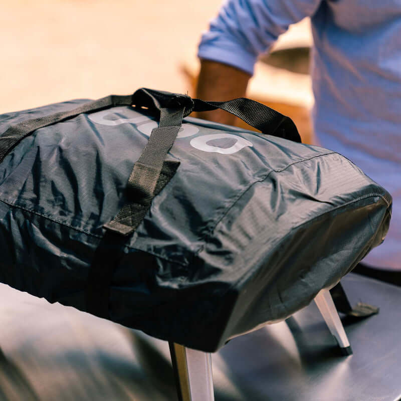 Person carrying Ooni Carry Cover for Ooni Koda 12, designed for easy transport and protection of the outdoor oven.