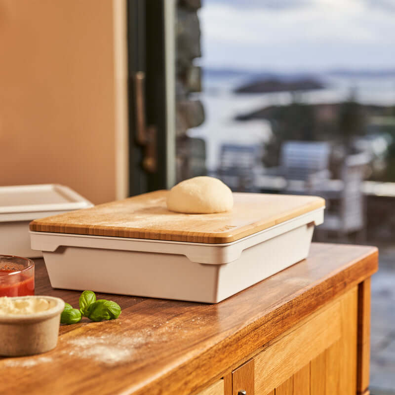 Bamboo Ooni Pizza Prep Lid being used for stretching pizza dough outdoors