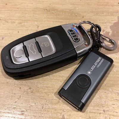 Ledlenser Flashlight K4R keychain light attached to car keys on a wooden surface.