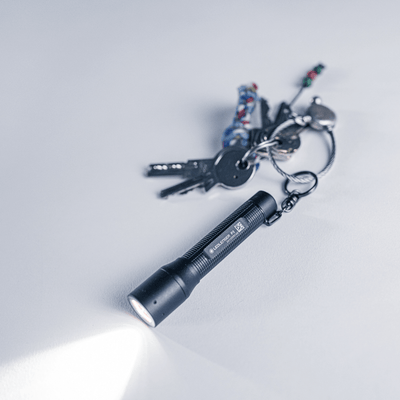 P3 tiny key flashlight with focus, keys in background, showcasing compact design and LED beam.