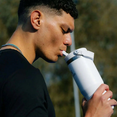 Man drinking from Stanley Classic IceFlow Flip Straw Tumbler - 30 oz / 890 ml during outdoor activity.