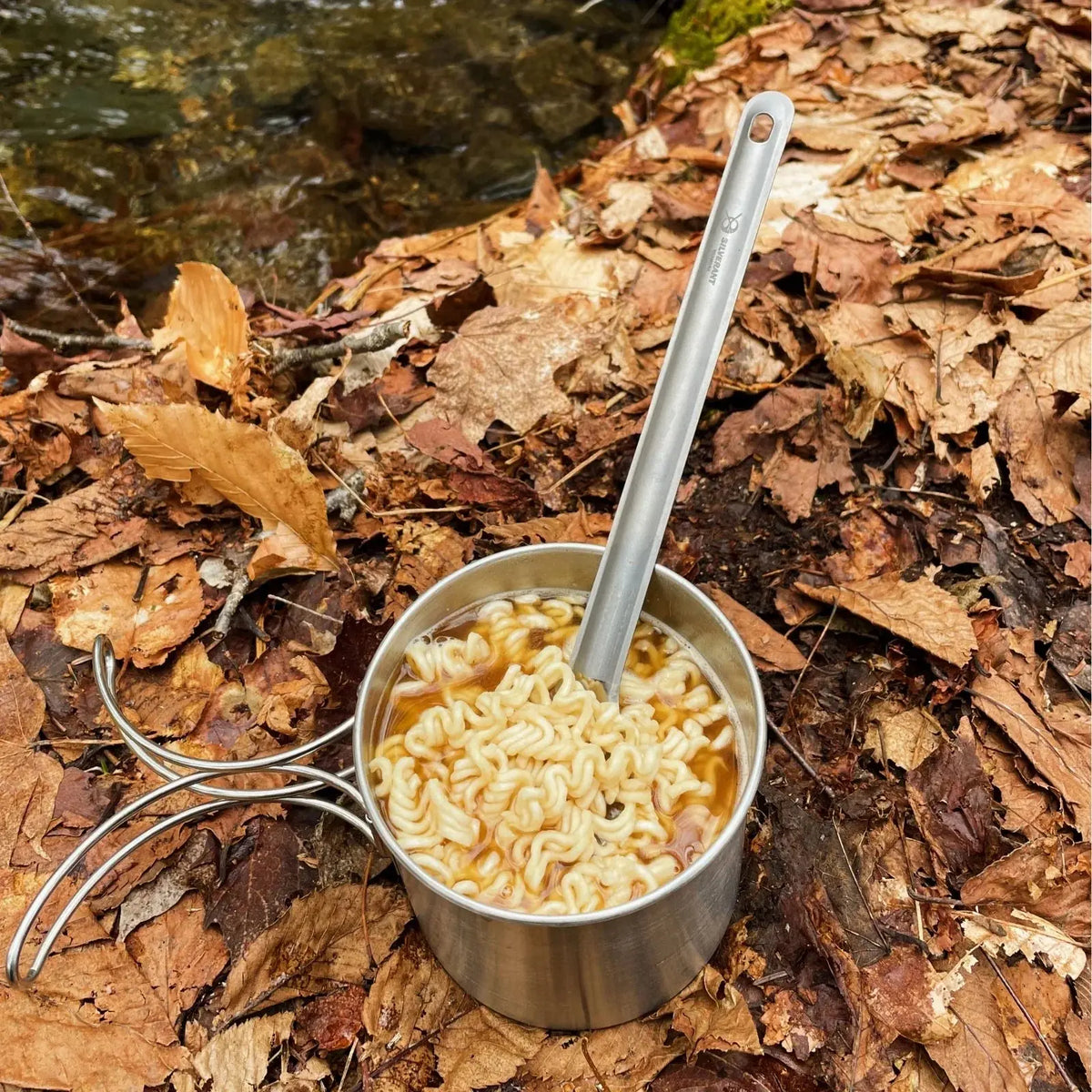 SilverAnt Long Handle Titanium Spork resting on a portable camping stove