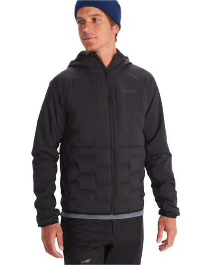 Man wearing Marmot Warmcube men's winter jacket in black with blue beanie, ideal for cold-weather adventures.