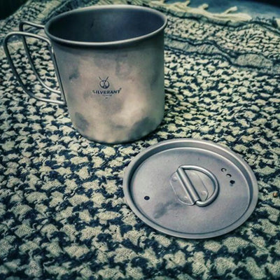 SilverAnt Ultralight Titanium Cup with Lid on a patterned outdoor cloth, ideal for UAE adventures and camping gear enthusiasts.