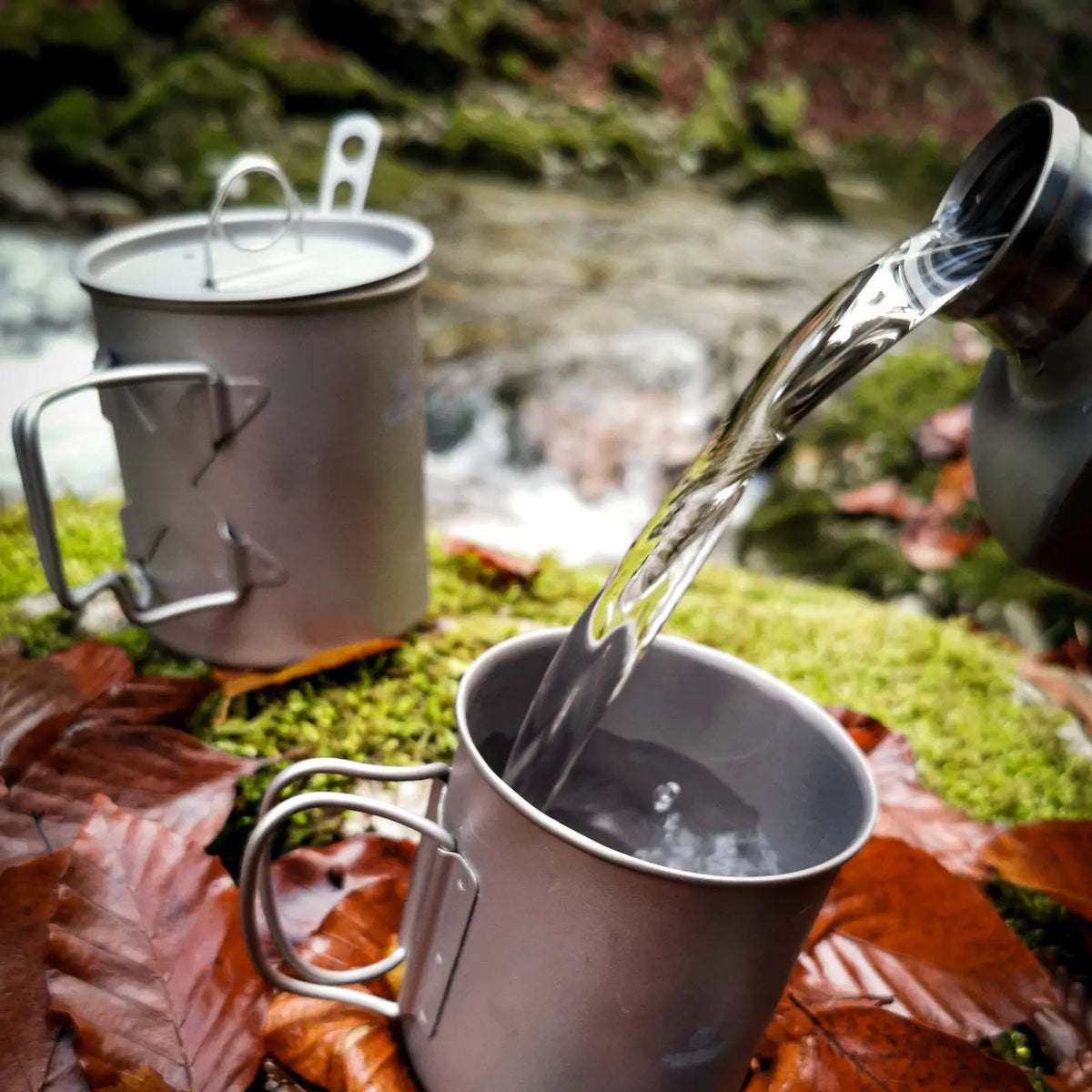 Pouring water into SilverAnt Ultralight Titanium Cup with Lid during outdoor adventure on autumn leaves