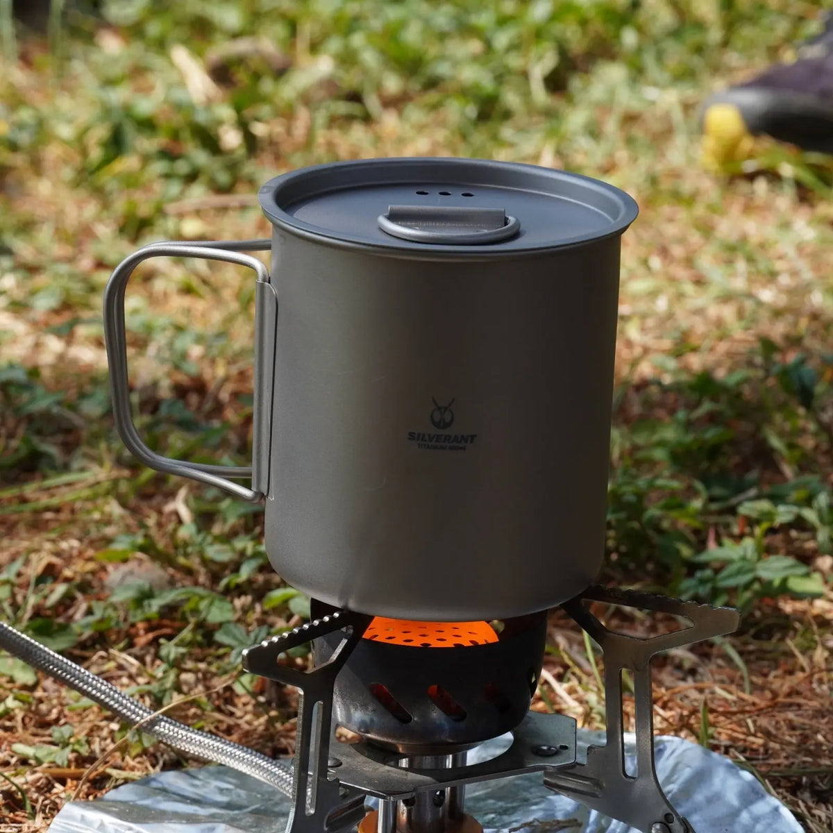 SilverAnt Ultralight Titanium Cup with Lid on a camping stove in a natural setting.