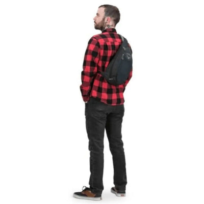 Man wearing Osprey Daylite Sling with red plaid shirt, showcasing the ambidextrous carry and sleek design.