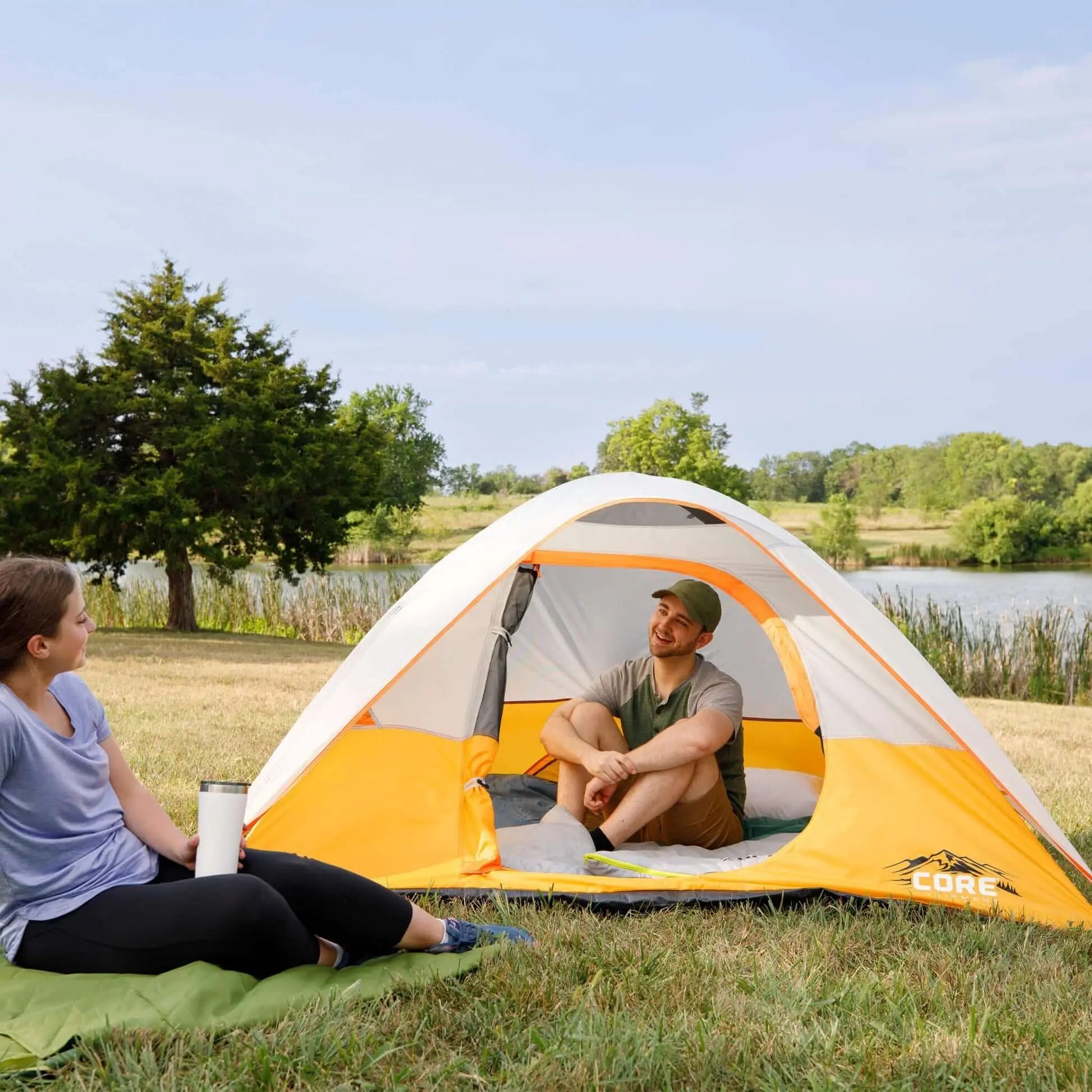 3 Person Dome Backpacking Tent - 7' x 7' set up by a lake with two people relaxing inside.