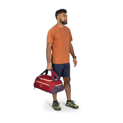 Man holding Osprey Daylite Duffel 30, a versatile bag with backpack, shoulder strap options for gym, travel, office; features zippered pockets.