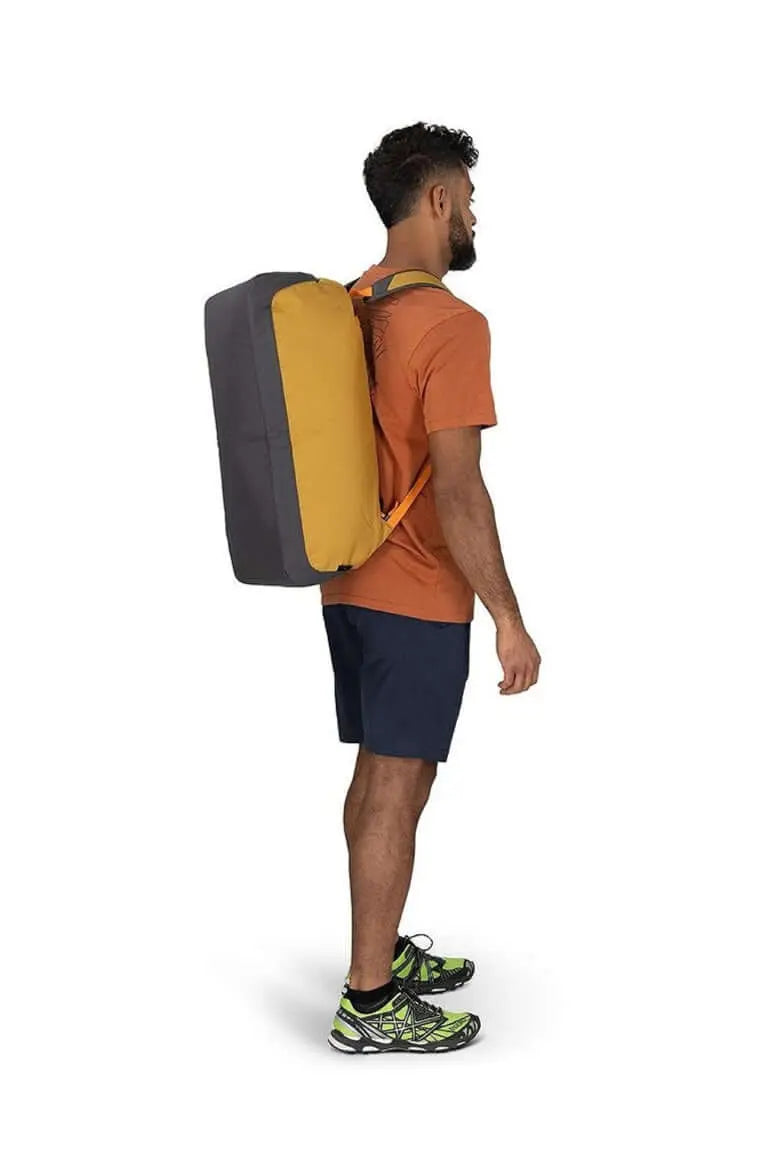 Man wearing Osprey Daylite Duffel 45 backpack in orange, showcasing versatile carry for travel and gym, with padded bottom and side pockets.