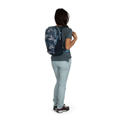 Woman wearing Osprey Daylite backpack in blue, showcasing its lightweight and durable design for versatile use on hikes and errands.