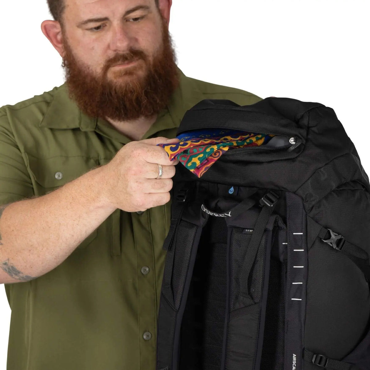 Man demonstrating the Osprey Talon 33 Extended Fit daypack with colorful interior, ideal for travel and day trips.