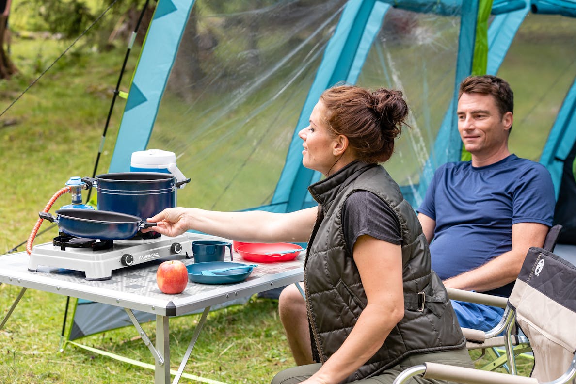Couple using Campingaz Camping Cook CV portable stove in a tent outside during a camping trip