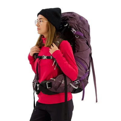 Woman wearing Osprey Aura AG 65 - Women backpack with suspension harness, in side profile view.