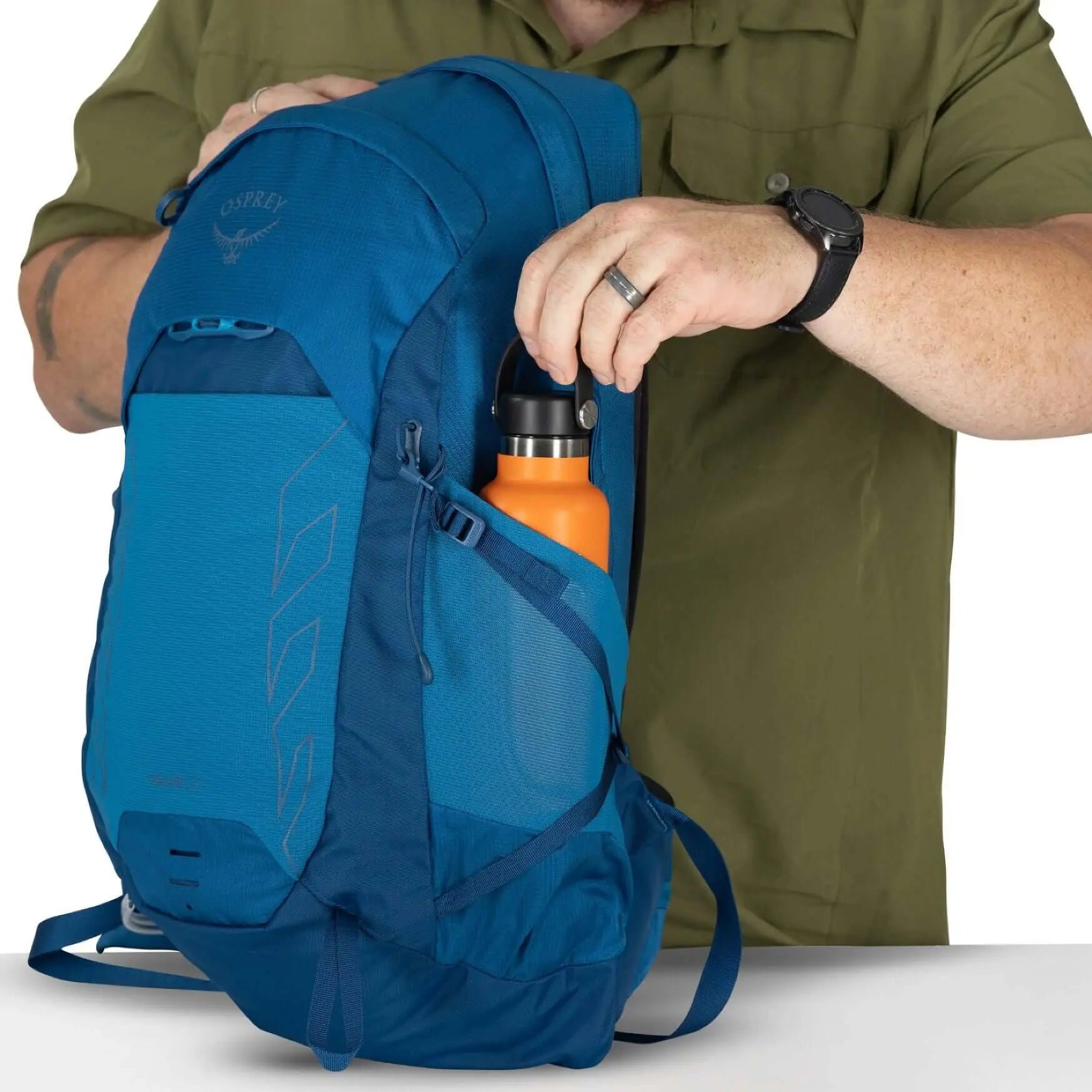 Person placing a water bottle into the side pocket of the Osprey Talon 22 Extended Fit - Men backpack.